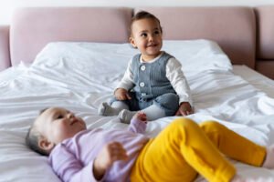 cute-babies-playing-with-each-other-bed-smiling-scaled.jpg